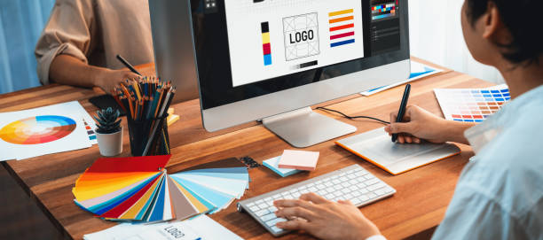 Designer working on a logo on a desktop monitor with colour swatches