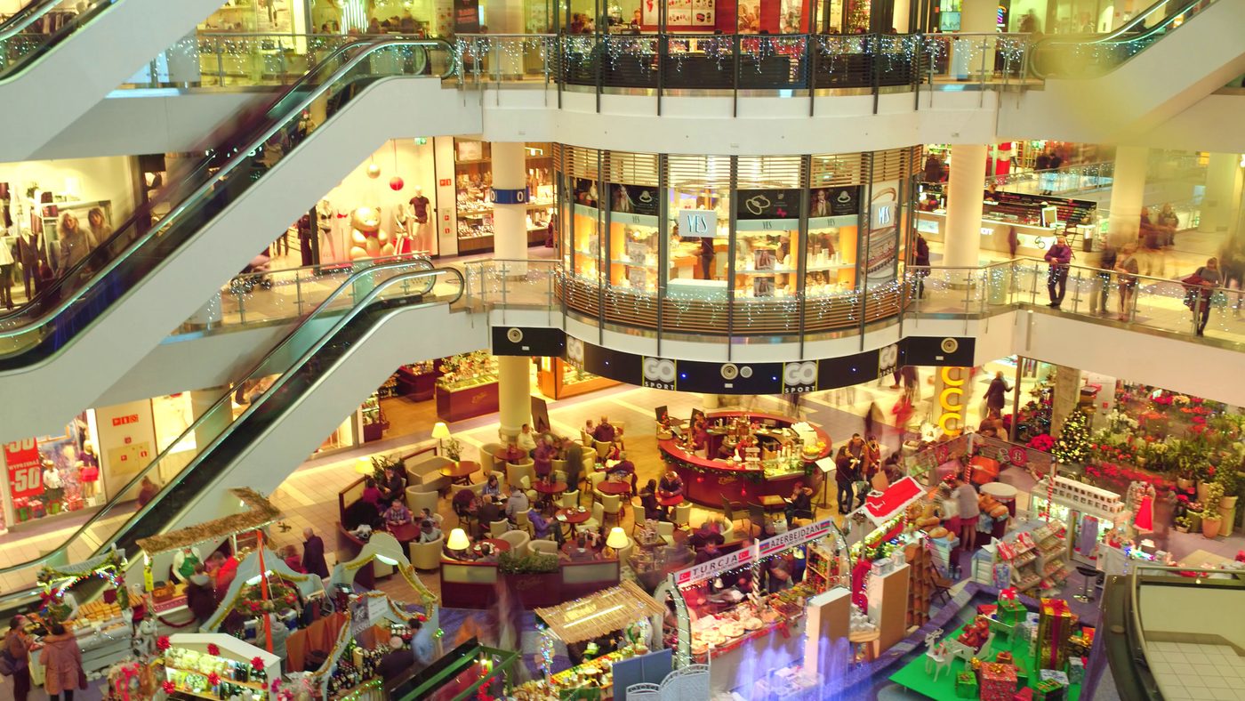 Busy shopping mall atrium seen from the escalators