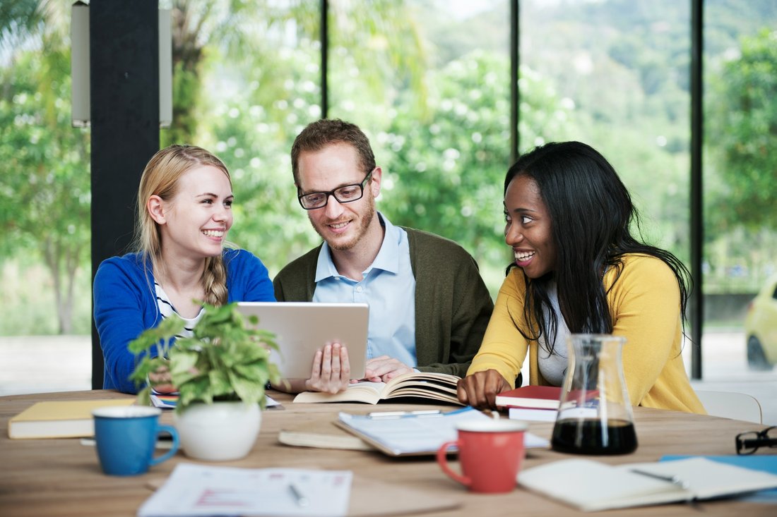 Three colleagues smiling while working together at a table